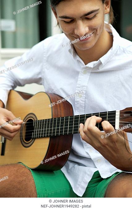 Teenage boy playing guitar, Sweden
