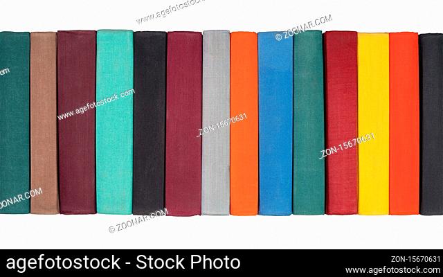 Stack of old hardcover books on bookshelf. Close-up view of multicolored vintage hardback books: black, brown, purple, turquoise, gray, orange, blue, green, red