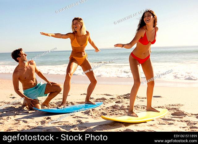 Caucasian group of friends surfing on the beach