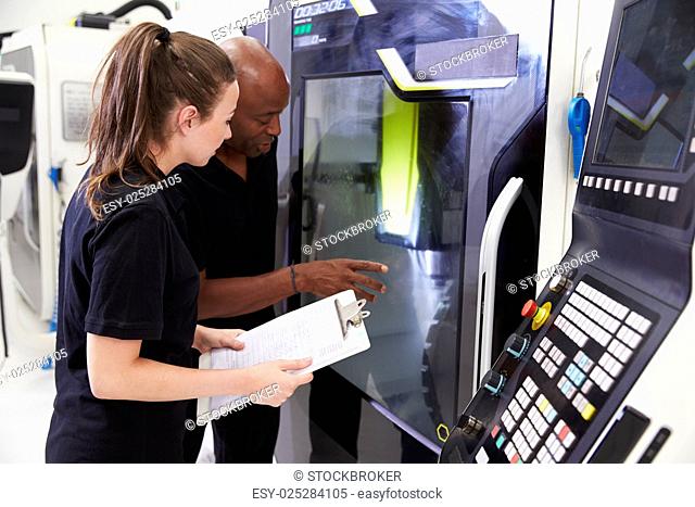 Female Apprentice Working With Engineer On CNC Machinery