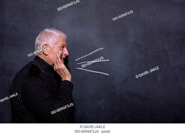 Portrait of senior man in front of blackboard