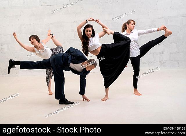 A man and women wearing office clothes doing yoga shot against white brick wall