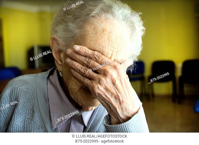 Portrait of a centennial woman in a elderly people home, hand covering her face
