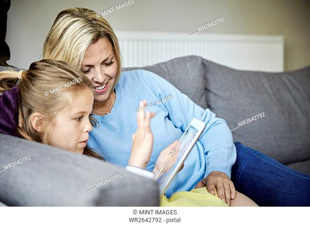 A family home. A mother and daughter using a digital tablet