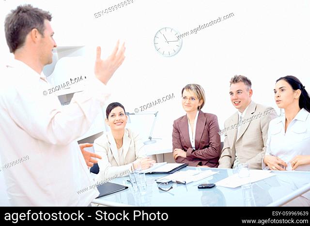 Businessman standing and explaining to four colleagues sitting around office table