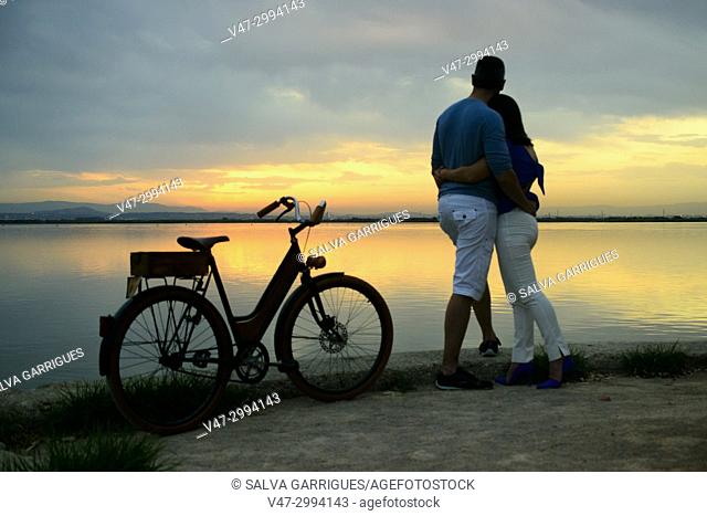 A wedding couple arrives by bicycle to the Albufera Natural Park to see the sun gate
