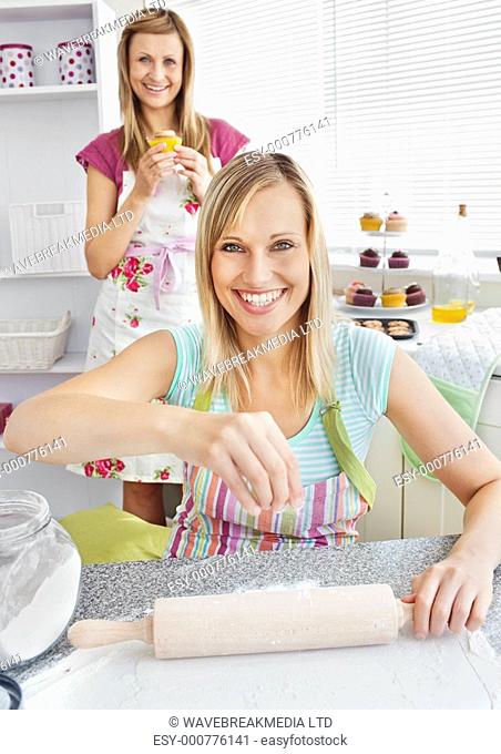 Animated female friends baking muffins in the kitchen smiling at the camera