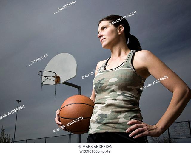 Woman holding basketball with net in background