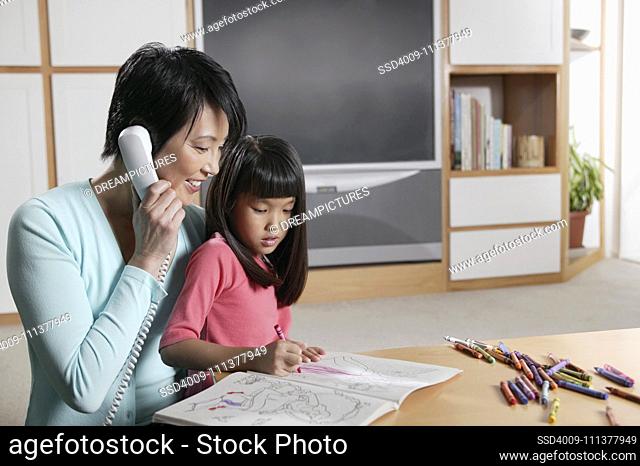 Mother talking on the phone as her daughter draws