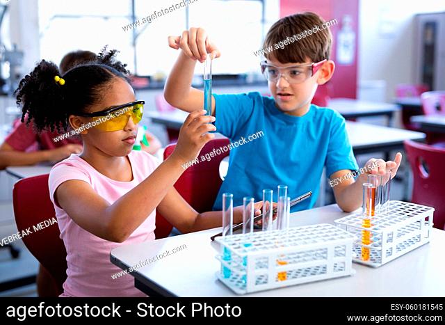 African american girl and caucasian boy holding test tube in science class at elementary school