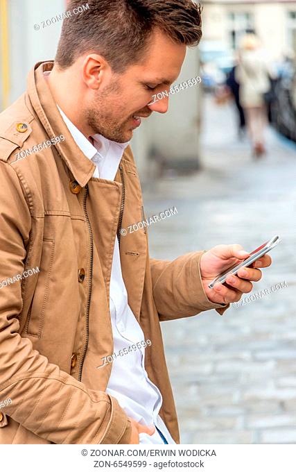 Ein Mann schreibt auf seinem Handy ein SMS. Kommunikation mit einem Smart phone