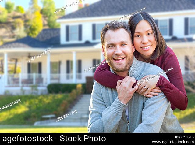 mixed-race caucasian and chinese couple in front yard of beautiful custom house