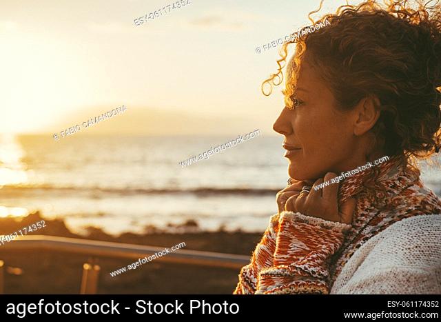 Enjoyed and serene lady dreaming and thinking outdoor with ocean beach and sunset light in background. Concept of happy lifestyle female people in outdoor...