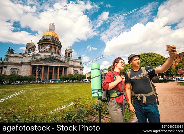Young couple of tourists taking selfies against the Isaac cathedral in Saint Petersburg - close up