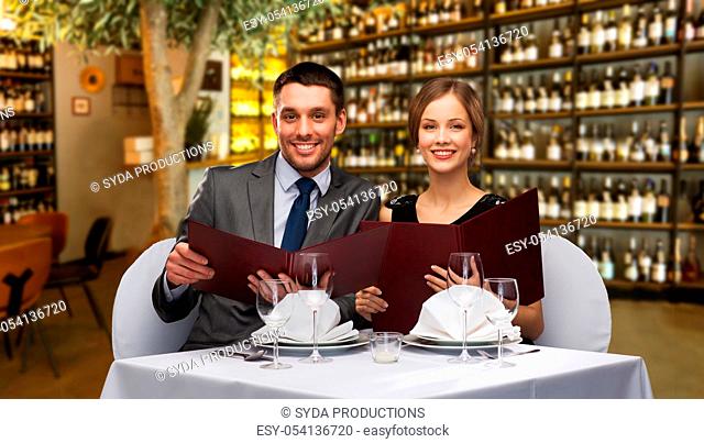 smiling couple with menus at restaurant