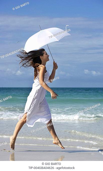 Woman with parasol skipping on beach