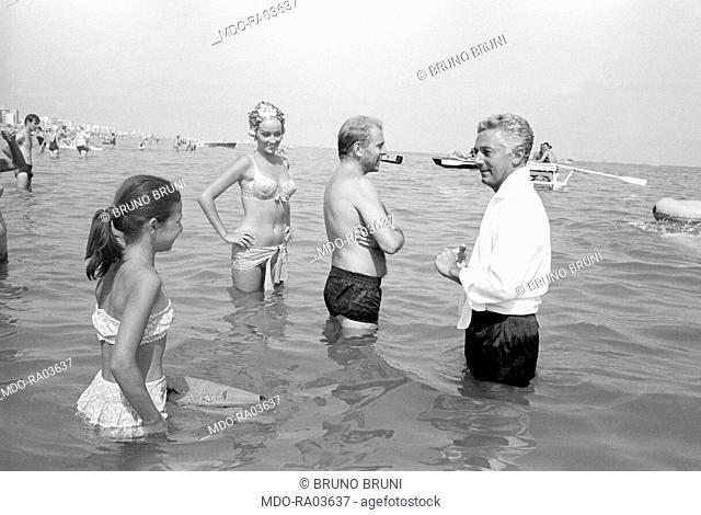Italian director Dino Risi illustrating a scene in the water to Italian actor Enrico Maria Salerno on the set of the film Weekend Wives. Italy, 1965