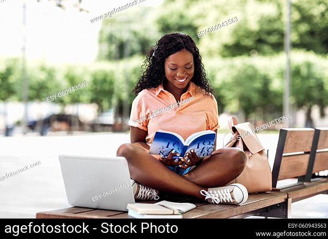 african student girl reading book in city