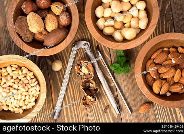 Utensils and nut filled bowls sit on wooden table