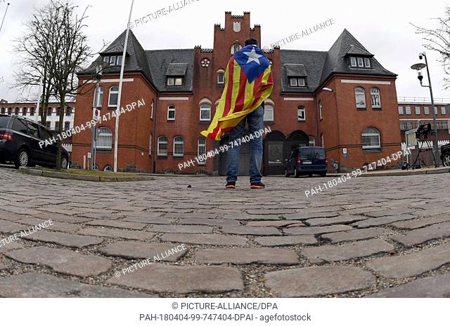 04 March 2018, Germany, Neumuenster: A demonstrator with a Estelada Blava - the flag of the catalonian nationalists - standing in front of the correctional...