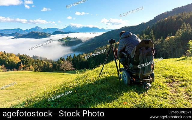 man on wheelchair taking photos of beautiful landscape