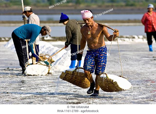 Man carries farmed salt in traditional shoulder baskets, Bangkok, Thailand