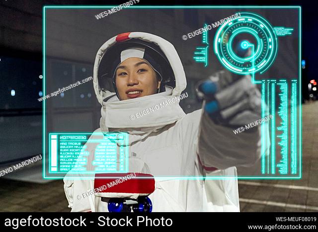 Young woman wearing astronaut costume touching device screen