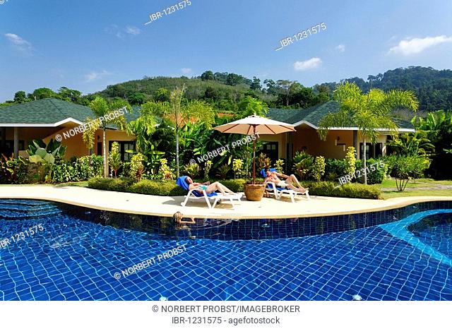 Woman on sun chair at pool, bungalows with green surroundings, Palm Garden Resort, Khao Lak, Phuket, Thailand, Asia