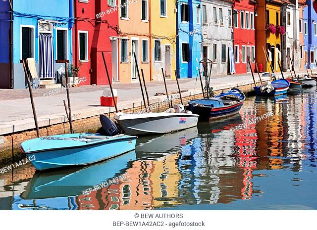 Venice Burano island canal small colored houses and the boats in sunny summer day
