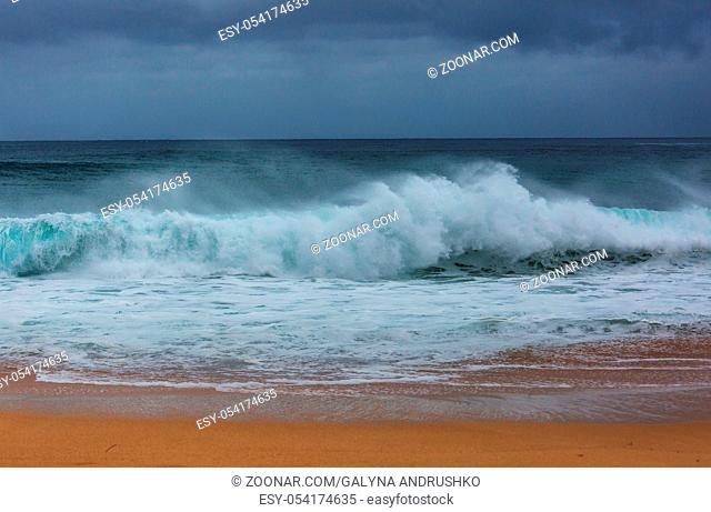 Blue wave on the beach. Blur background and sunlight spots. Peaceful natural background