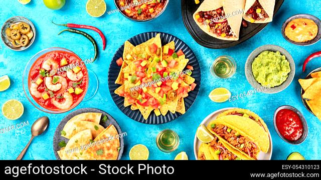 A panorama of Mexican food, many dishes of the cuisine of Mexico, flat lay, top shot on a blue background. Nachos, tequila, guacamole, quesadillas