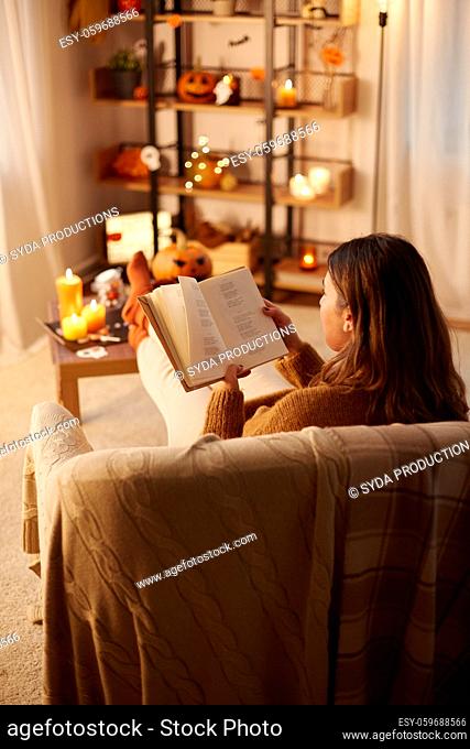young woman reading book at home on halloween