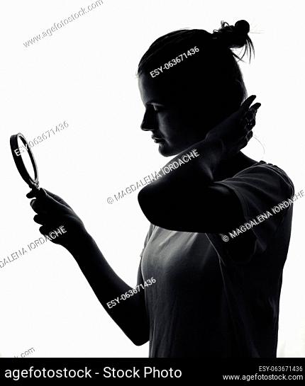 A charming young girl silhouette looking in the mirror in studio