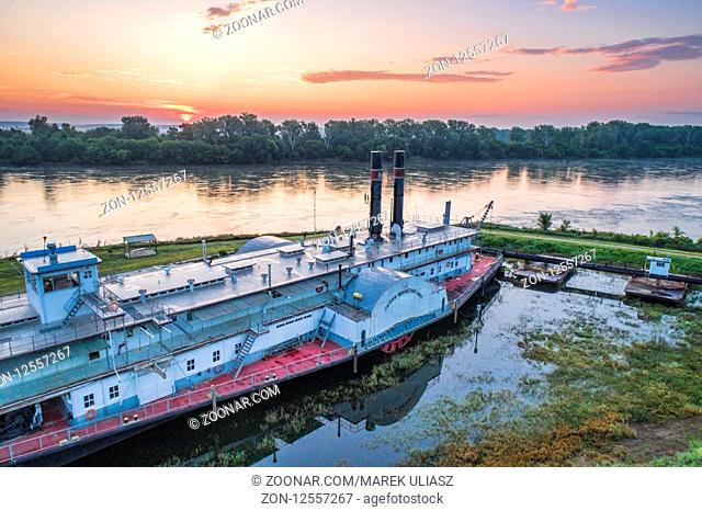 Brownville, NE, USA - July 30, 2018: Hazy siunrise over MIssouri River with the historic dredge, Captain Meriwether Lewis, in a dry dock on a shore
