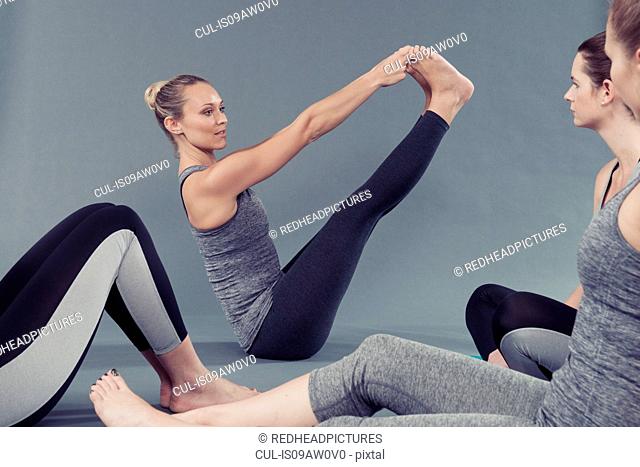 Young women doing stretching exercise, grey background