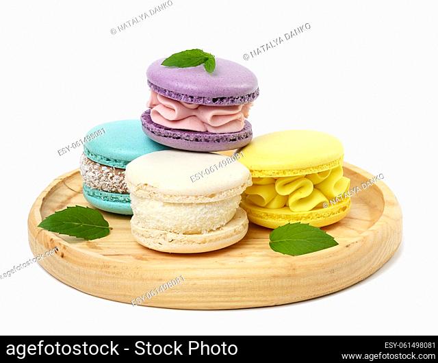 Multi -colored baked macaroons on a wooden plate, white isolated background