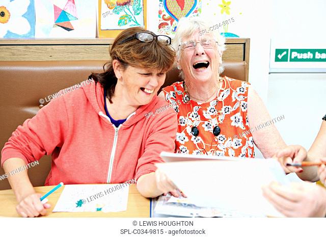 MODEL RELEASED. Dementia art therapy participants. Woman with dementia (right) and a community worker (left) at an art therapy group