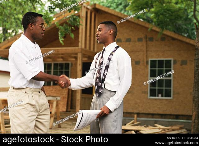 African businessmen shaking hands outside new home