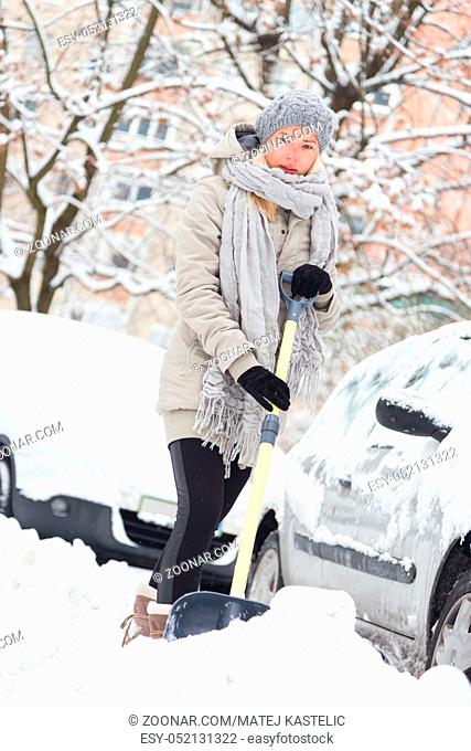 Independent woman shoveling her parking lot after a winter snowstorm
