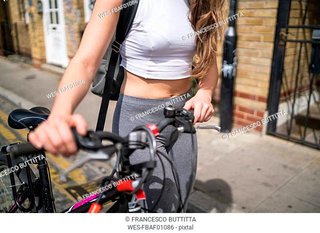 Young woman pushing her bicycle in the city