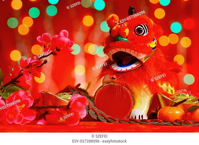 Chinese new year festival decorations, miniature dancing lion and ancient money on red glitter background