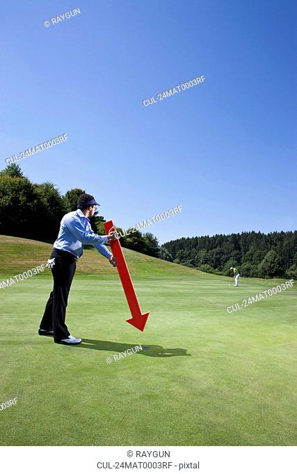 Caddy pointing at a hole on golf course