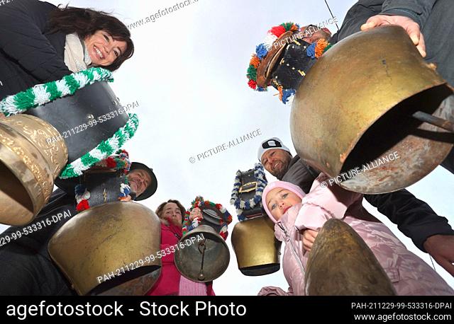 29 December 2021, Bavaria, Rettenberg: Landlords Angelika Soyer (l) and Peter Soyer (2nd from left) as well as neighbors and holiday guests ring cowbells and...