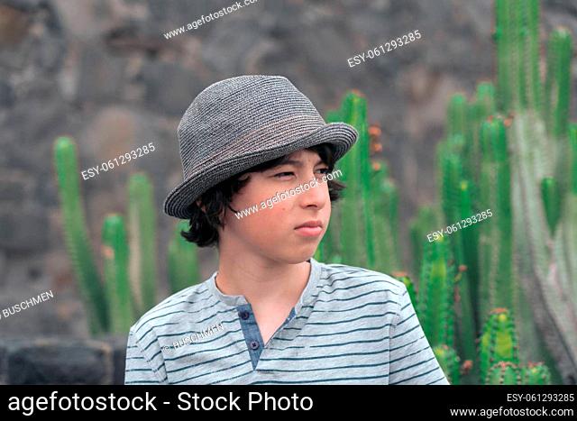 Portrait of a teenager in a polo shirt and a hat against the background of cacti