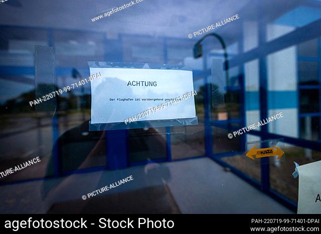 18 July 2022, Mecklenburg-Western Pomerania, Parchim: A small sign reading ""ATTENTION The airport is temporarily closed"" hangs on the glass door in the...