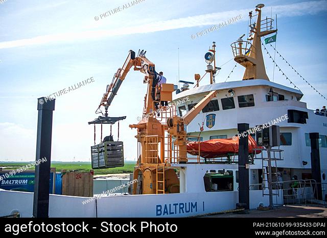 10 June 2021, Lower Saxony, Neßmersiel: A cold-blooded horse is lifted onto the passenger ferry ""Baltrum I"" in the port of Neßmersiel to be shipped to the...