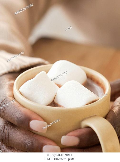 African woman holding cup of hot chocolate and marshmallows