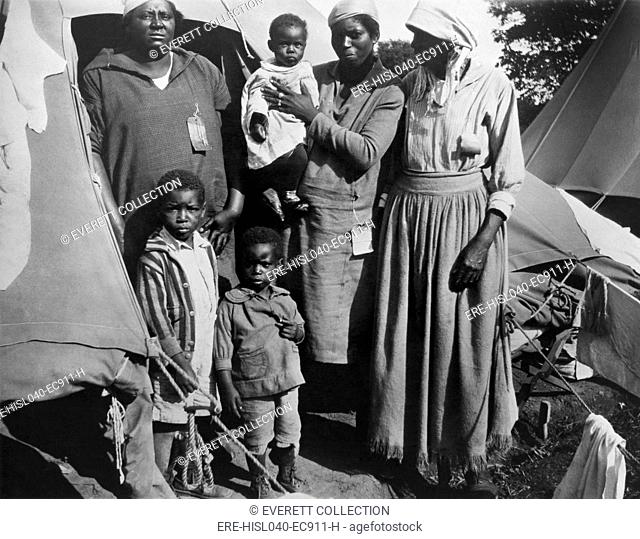 African American women with three children during the 1927 Mississippi River flood. The Red Cross provided relief at segregated refugee camps on the Vicksburg...