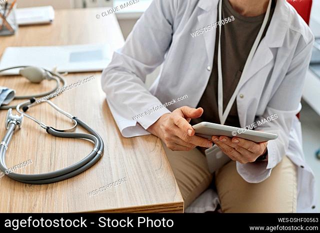 Doctor using tablet PC sitting at desk in clinic