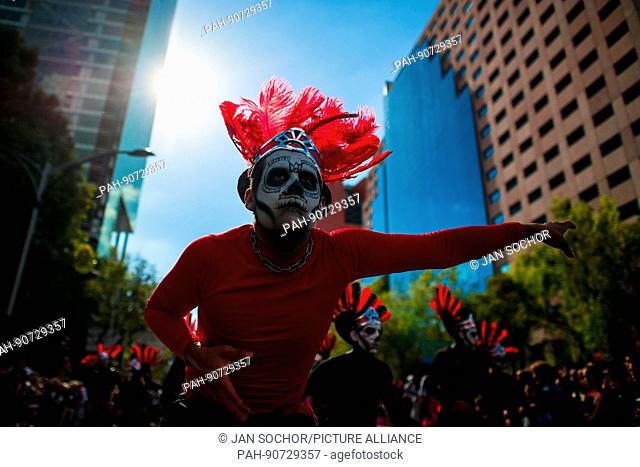 Mexican men, wearing feather headgears inspired by Aztecs, dance on the street during the Day of the Dead festival in Mexico City, Mexico, 29 November 2016
